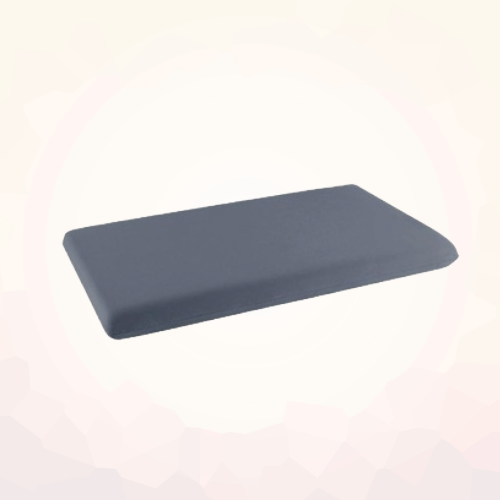 Dark gray low-profile rectangular lash pillow shown at an angle on a light geometric background.
