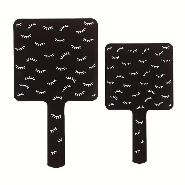 Two black paddle boards with white eyelash pattern on a white background