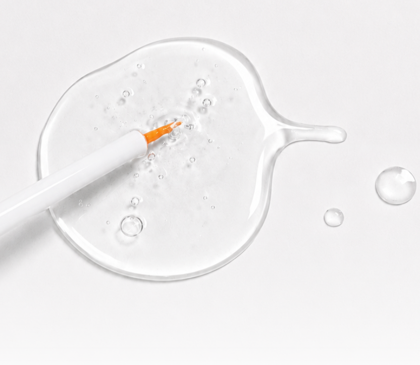 Clear texture of Snow Lash Total Clinic Essence shown with a fine applicator brush for professional lash lift services