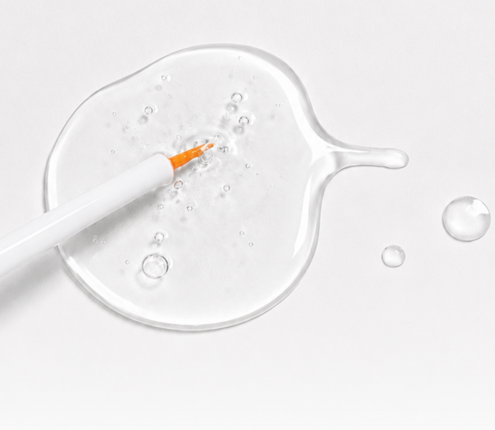 Clear texture of Snow Lash Total Clinic Essence shown with a fine applicator brush for professional lash lift services